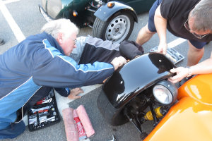 Mike and Richard struggle to get the broken mudguard off Griff's Car